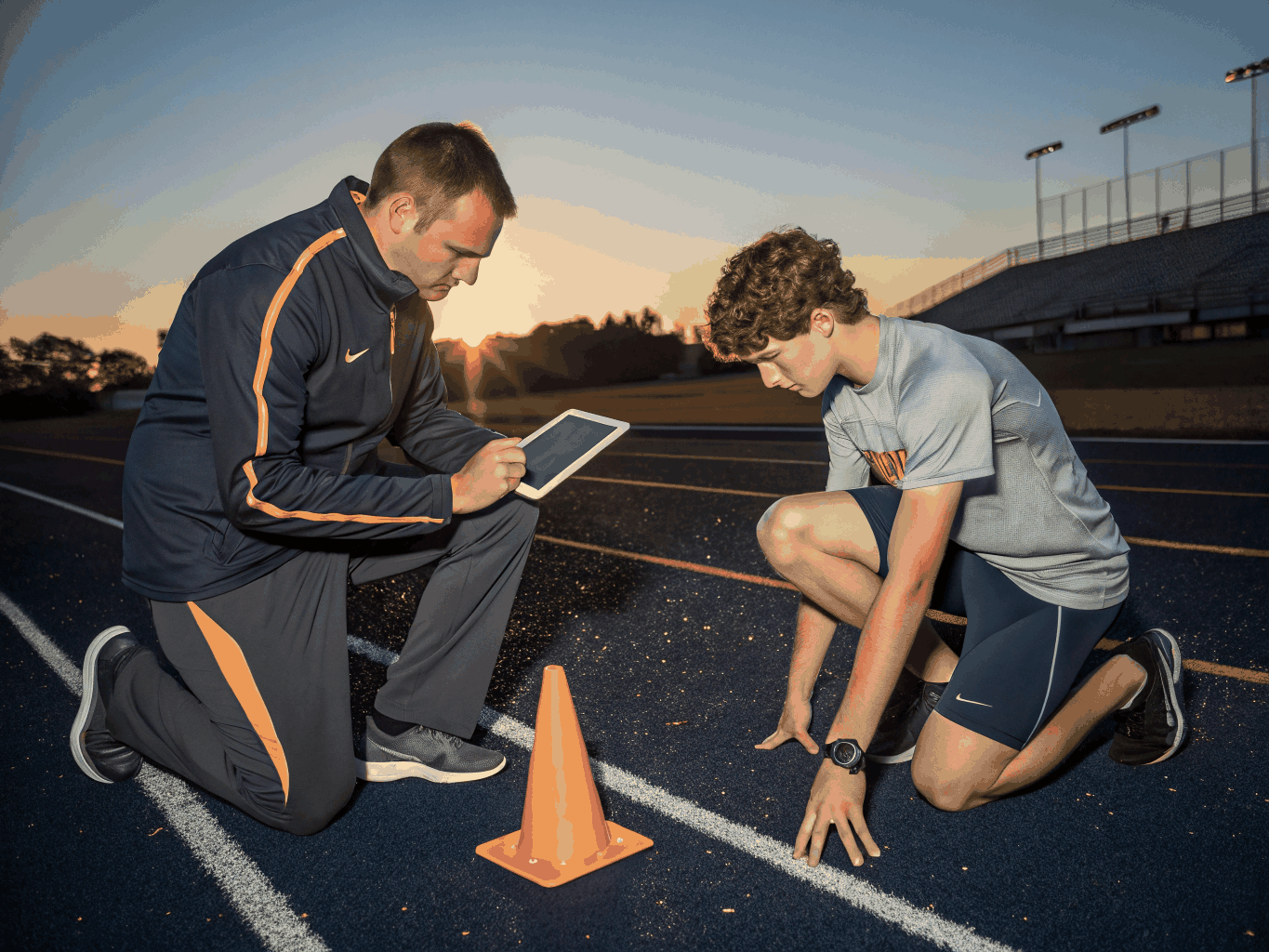 Sports performance specialist conducting a functional biomechanics movement screening with a young athlete on turf